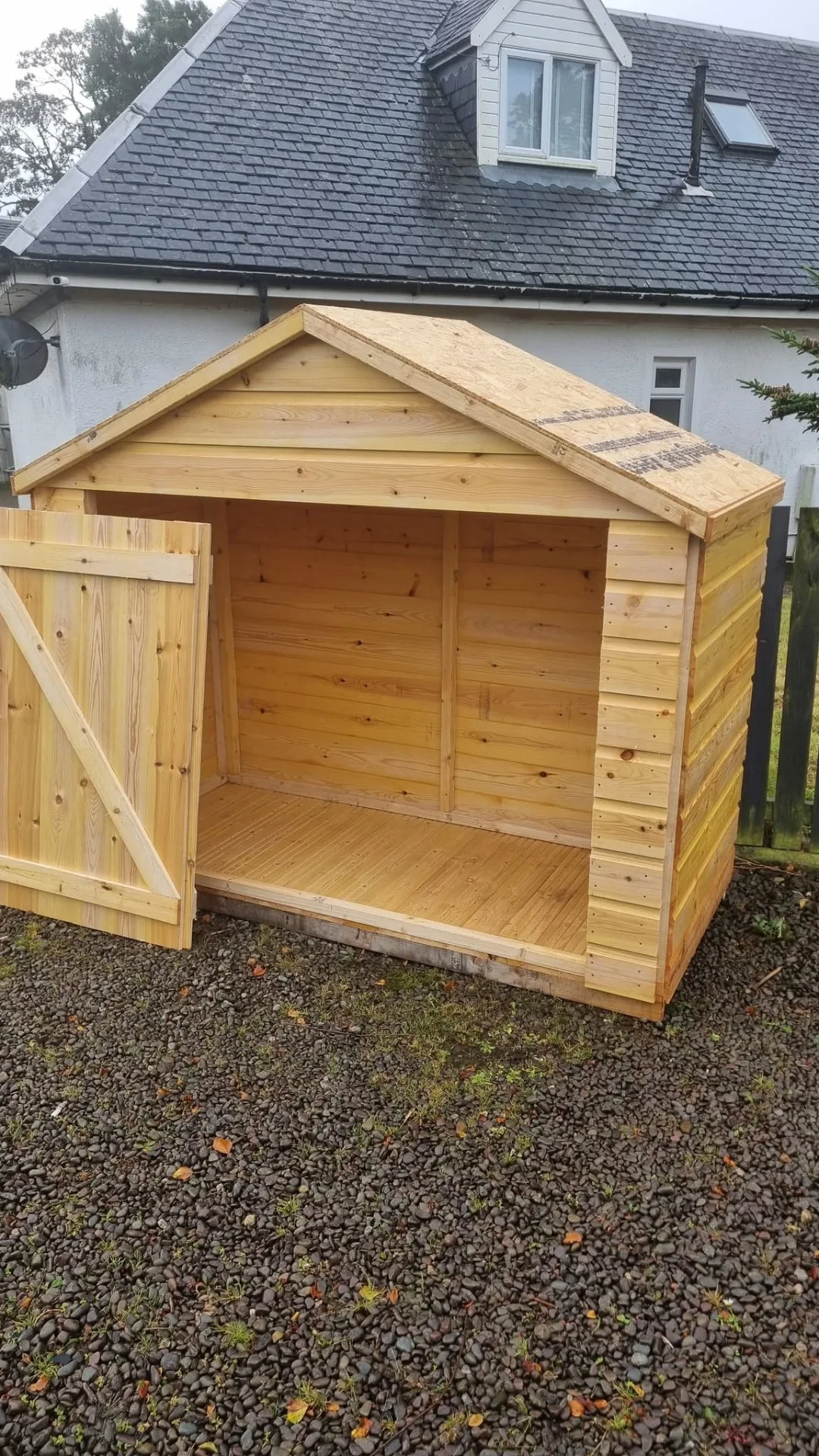Apex-roof timber shed with its door open showing the boarded interior